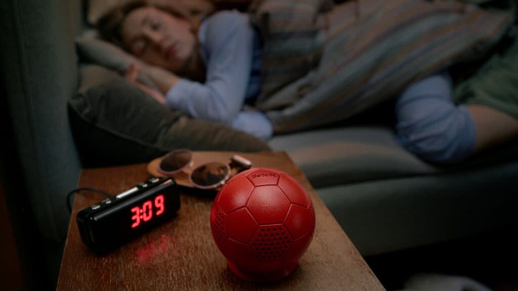 Betclic Red Noise — czerwona piłka-głośnik obok budzika, w tle śpiąca osoba